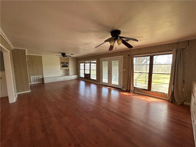 unfurnished living room featuring a ceiling fan, visible vents, ornamental molding, and wood finished floors