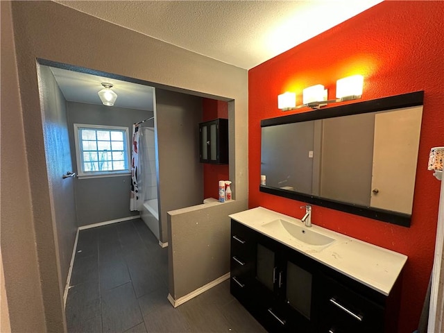 full bath with a textured ceiling, shower / bath combo, vanity, and baseboards