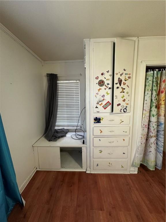 unfurnished bedroom with dark wood-style floors, baseboards, and crown molding