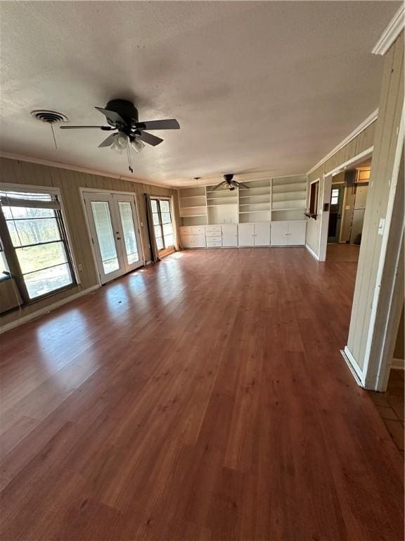 unfurnished living room featuring ornamental molding, dark wood finished floors, visible vents, and a ceiling fan