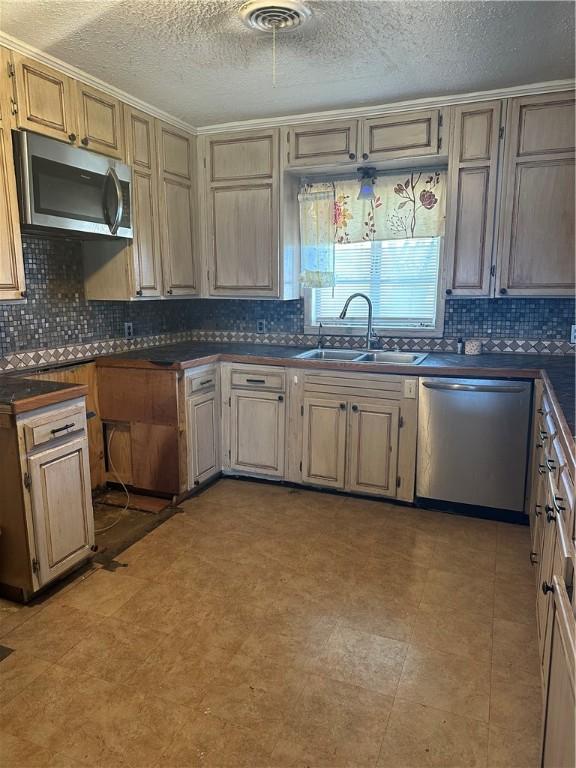 kitchen with stainless steel appliances, dark countertops, tasteful backsplash, visible vents, and a sink