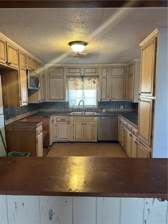 kitchen with dark countertops, tasteful backsplash, appliances with stainless steel finishes, and a sink