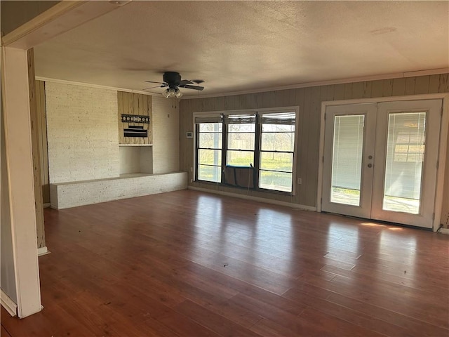 empty room with a textured ceiling, wood finished floors, a ceiling fan, french doors, and crown molding