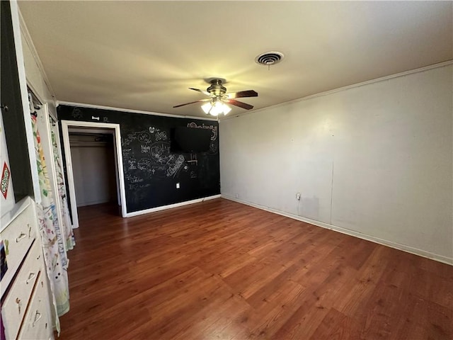 empty room with ceiling fan, wood finished floors, visible vents, and crown molding