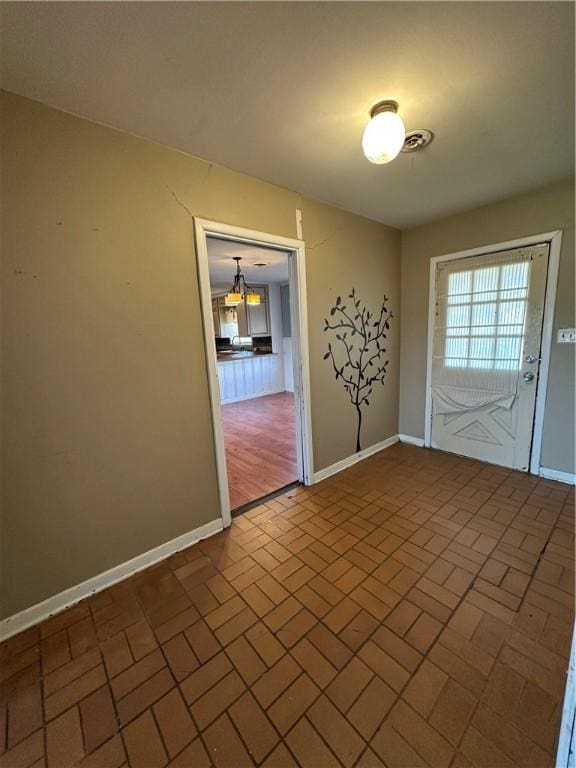 spare room featuring brick floor and baseboards