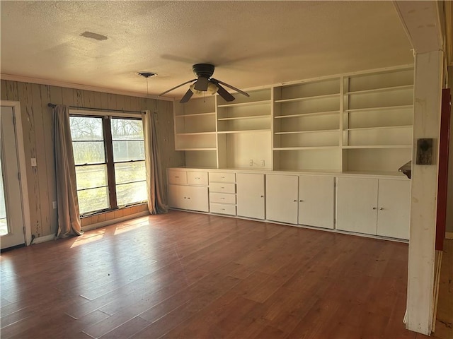 unfurnished room with a textured ceiling, ceiling fan, dark wood-style flooring, and visible vents