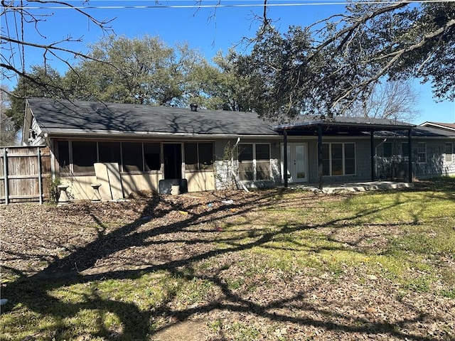 back of property with a sunroom, fence, and a lawn