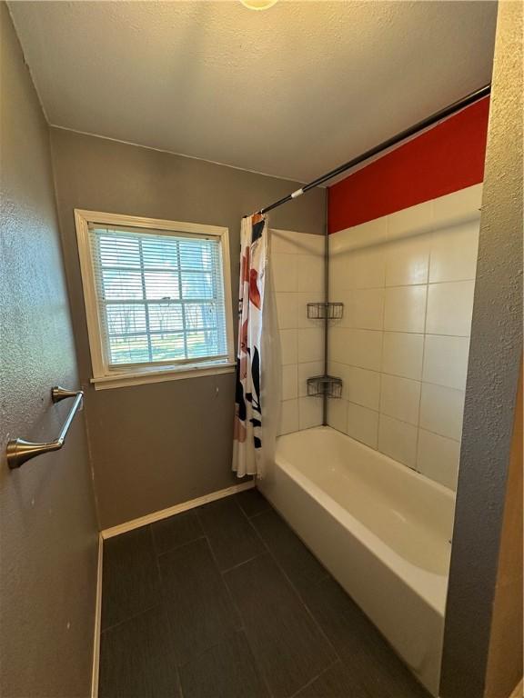 bathroom featuring shower / bath combo, tile patterned flooring, a textured ceiling, and baseboards