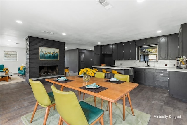 dining space with sink, dark hardwood / wood-style floors, and a brick fireplace