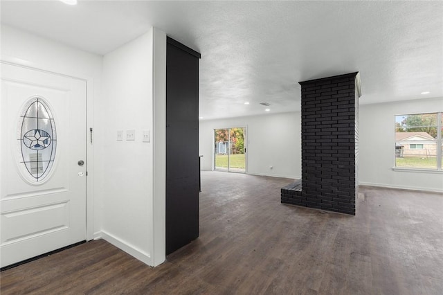 foyer with dark hardwood / wood-style floors, ornate columns, and a textured ceiling