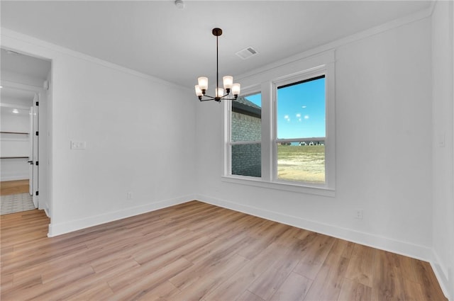 unfurnished room with crown molding, light hardwood / wood-style floors, and a notable chandelier