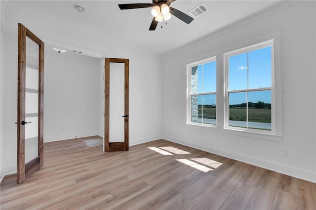 empty room featuring ceiling fan, light wood-type flooring, and french doors