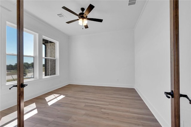 empty room with ceiling fan, light hardwood / wood-style floors, ornamental molding, and french doors