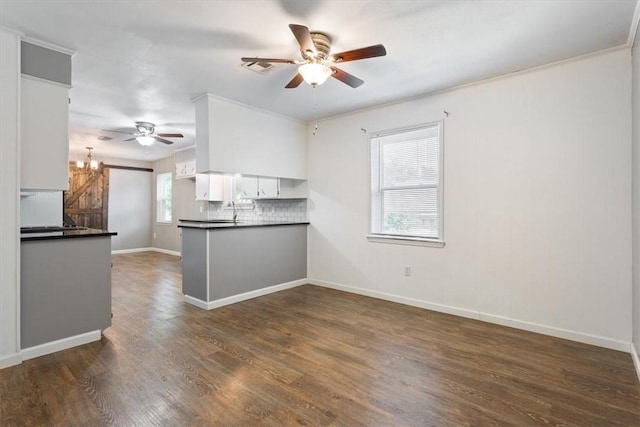 kitchen featuring dark hardwood / wood-style flooring, backsplash, kitchen peninsula, white cabinets, and ceiling fan with notable chandelier