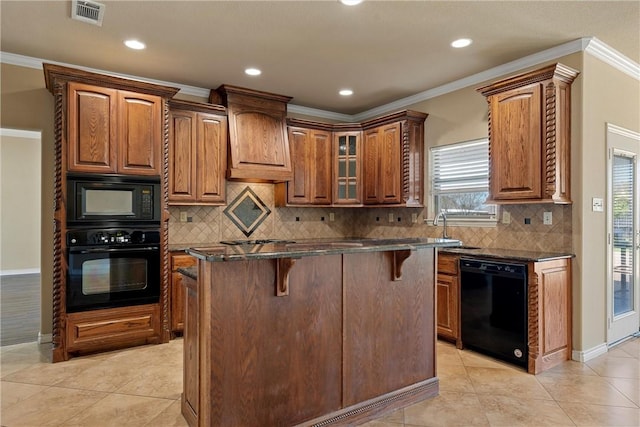 kitchen featuring black appliances, a center island, a healthy amount of sunlight, and a breakfast bar