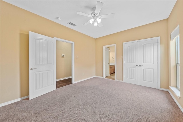 unfurnished bedroom featuring ceiling fan, light colored carpet, connected bathroom, and a closet