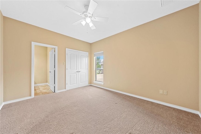 unfurnished bedroom with ceiling fan, light colored carpet, and a closet