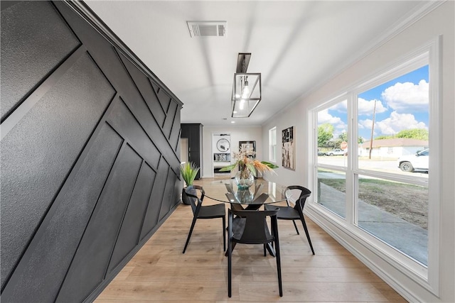 dining room with crown molding and light wood-type flooring