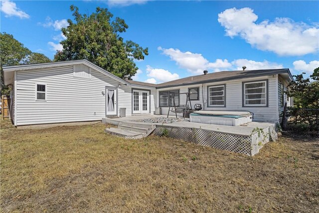 rear view of property with french doors, a wooden deck, and a lawn