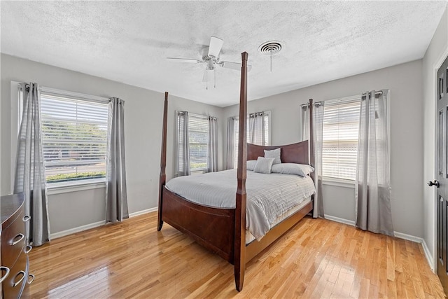 bedroom with a textured ceiling, light wood-type flooring, and ceiling fan