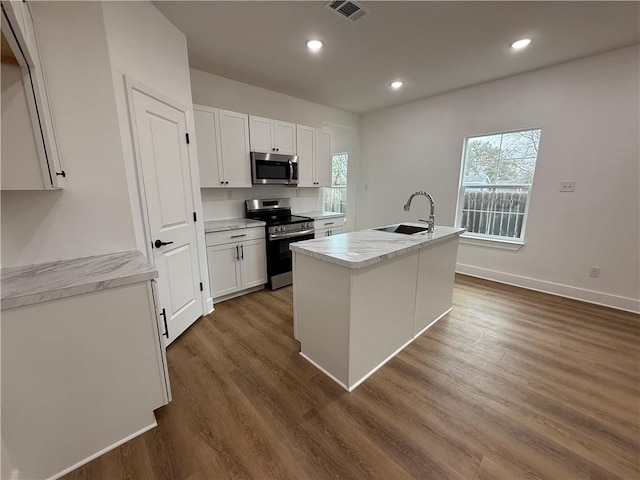 kitchen with white cabinetry, appliances with stainless steel finishes, sink, and a kitchen island with sink