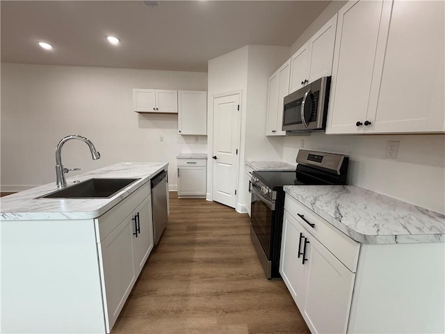 kitchen featuring sink, white cabinetry, a kitchen island with sink, stainless steel appliances, and light hardwood / wood-style floors