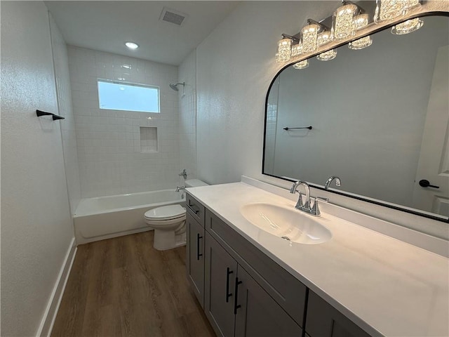 full bathroom with hardwood / wood-style flooring, tiled shower / bath, vanity, and toilet