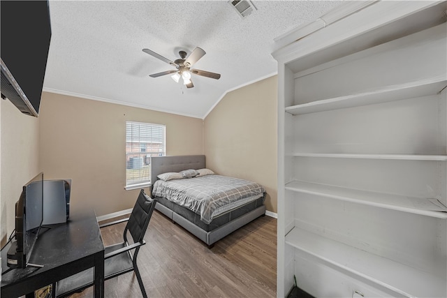 bedroom featuring ceiling fan, ornamental molding, vaulted ceiling, and wood-type flooring