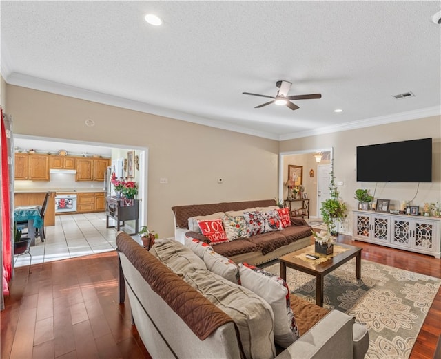 living room with a textured ceiling, ceiling fan, and crown molding