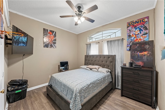 bedroom with hardwood / wood-style floors, a textured ceiling, ceiling fan, and ornamental molding