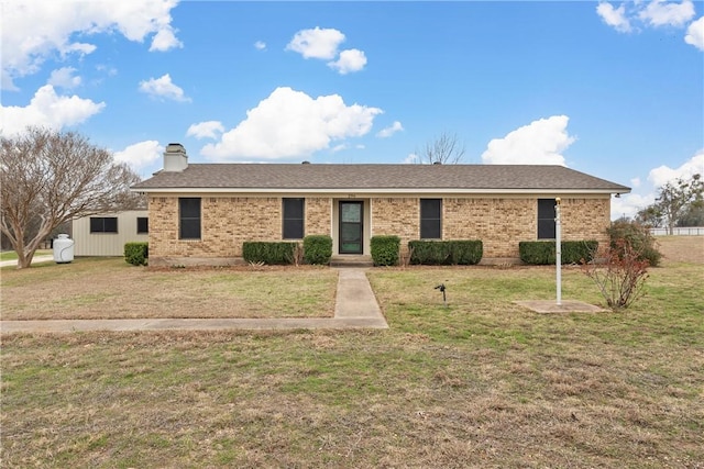 ranch-style house with a shingled roof, a front yard, brick siding, and a chimney