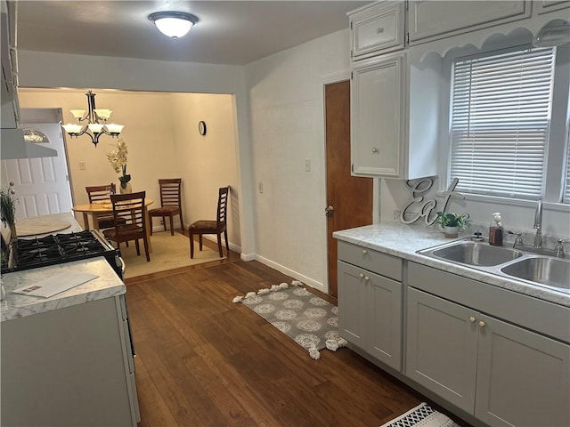 kitchen featuring dark wood-type flooring, sink, hanging light fixtures, gray cabinets, and a notable chandelier