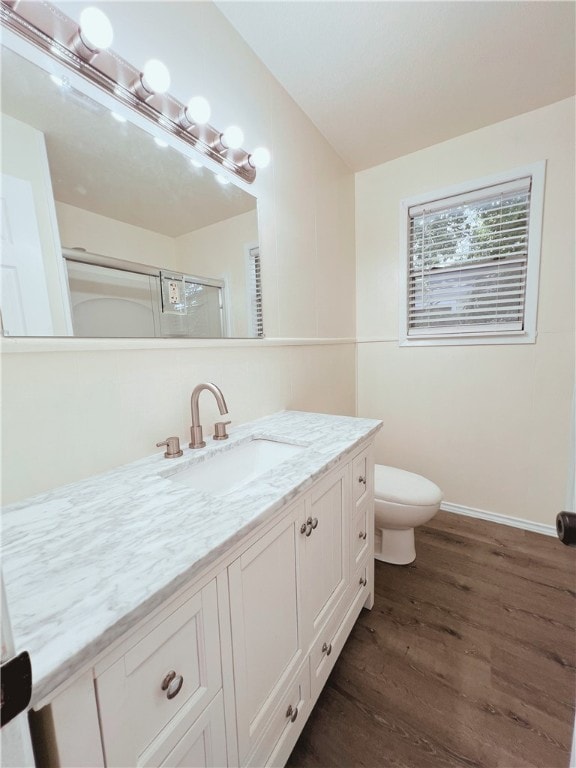 bathroom with hardwood / wood-style floors, vanity, toilet, and a shower with door