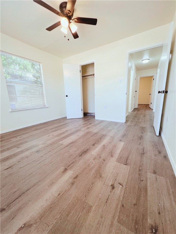 unfurnished bedroom with ceiling fan, a closet, and light hardwood / wood-style flooring