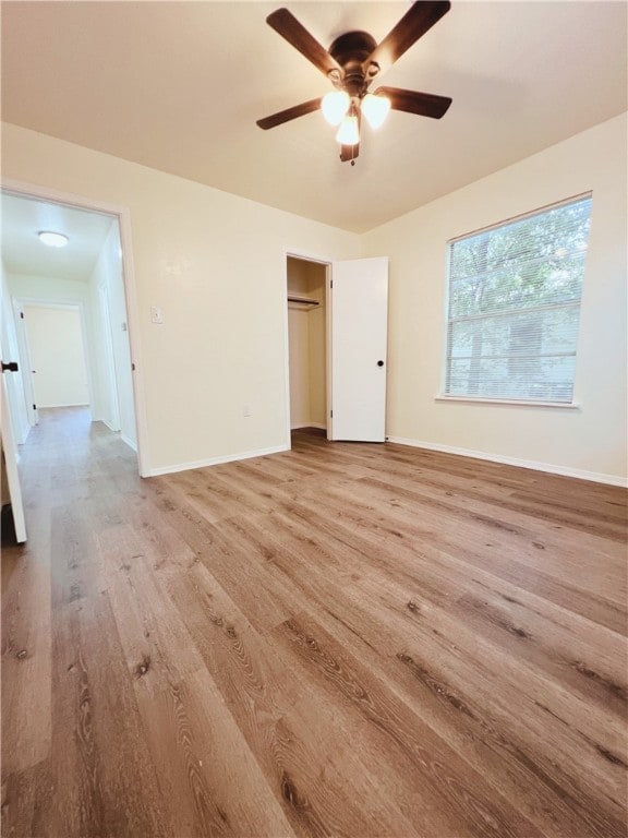 unfurnished bedroom with a closet, light hardwood / wood-style floors, a spacious closet, and ceiling fan