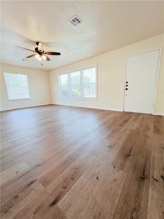 interior space with ceiling fan, wood-type flooring, and a textured ceiling