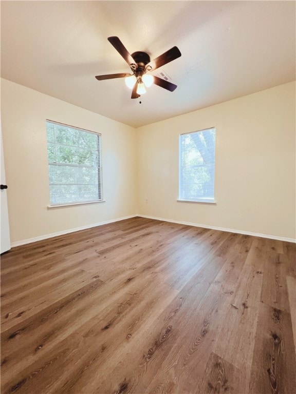 unfurnished room featuring hardwood / wood-style floors, ceiling fan, and a wealth of natural light