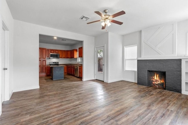 unfurnished living room featuring a fireplace, dark hardwood / wood-style floors, ceiling fan, and sink