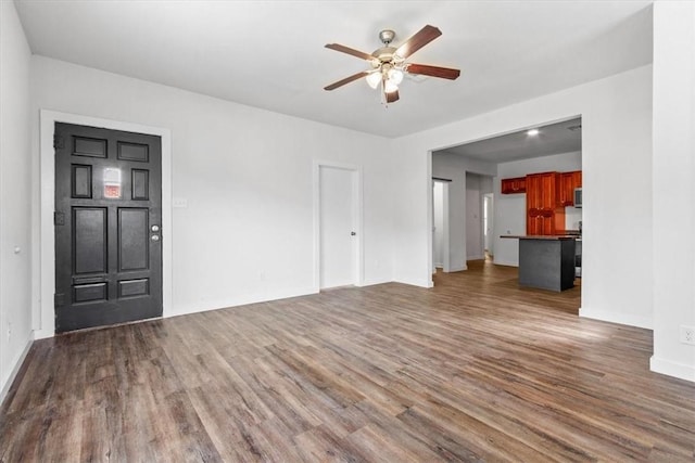 unfurnished living room featuring ceiling fan and dark wood-type flooring