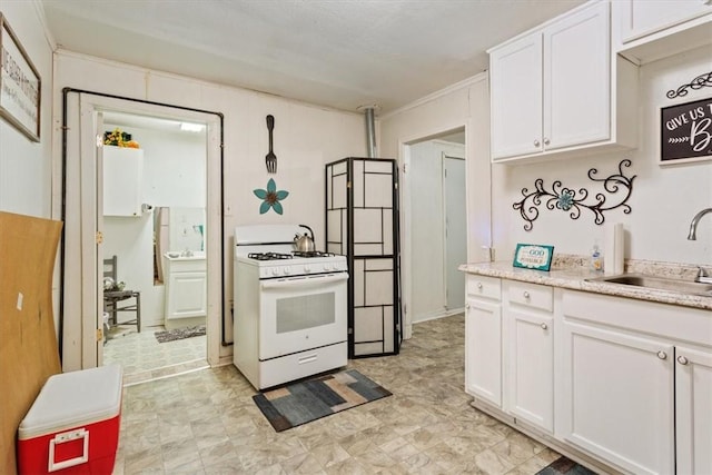 kitchen featuring white range with gas stovetop, white cabinetry, crown molding, and sink