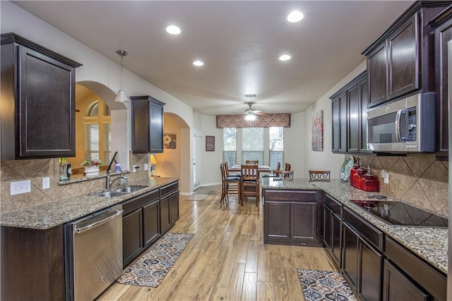 kitchen with tasteful backsplash, light wood-type flooring, decorative light fixtures, and appliances with stainless steel finishes