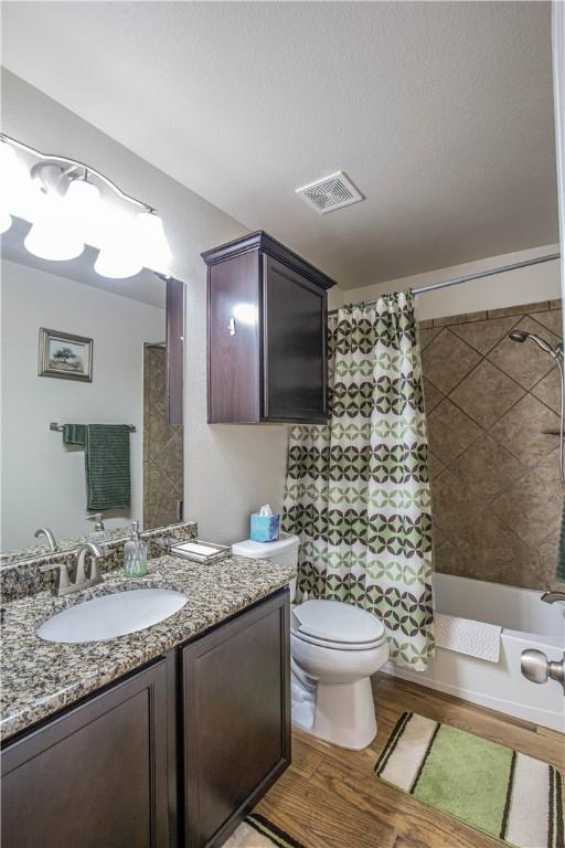 full bathroom featuring shower / bathtub combination with curtain, toilet, vanity, and hardwood / wood-style flooring