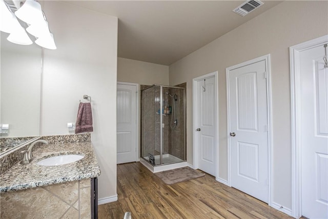 bathroom featuring vanity, wood-type flooring, and a shower with door