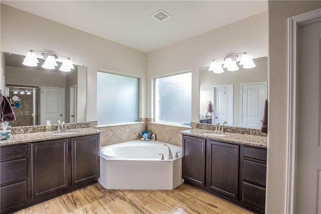 bathroom with hardwood / wood-style floors, vanity, and independent shower and bath