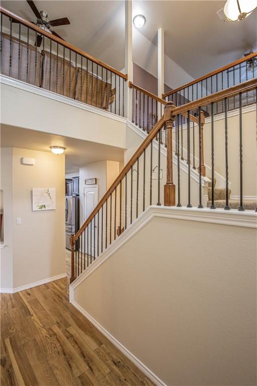 stairs with a towering ceiling, hardwood / wood-style flooring, and ceiling fan