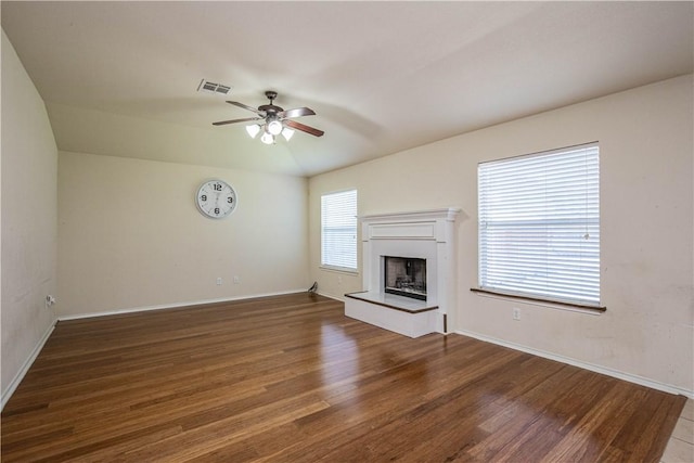 unfurnished living room with plenty of natural light, ceiling fan, and dark hardwood / wood-style flooring