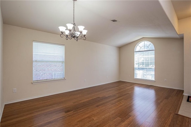 spare room featuring dark hardwood / wood-style flooring, an inviting chandelier, and lofted ceiling