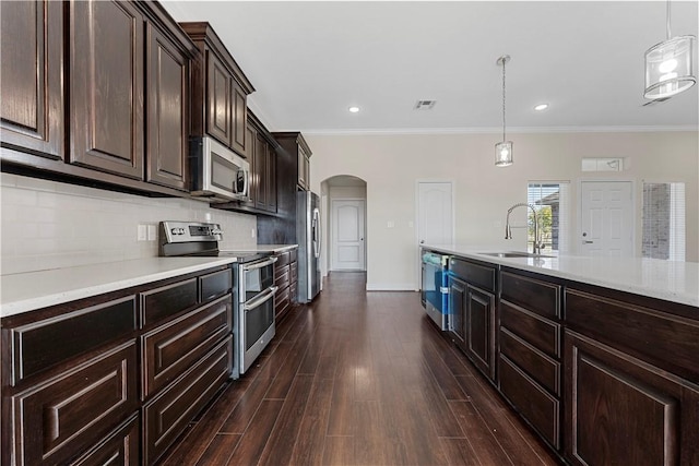 kitchen with sink, dark wood-type flooring, hanging light fixtures, and appliances with stainless steel finishes