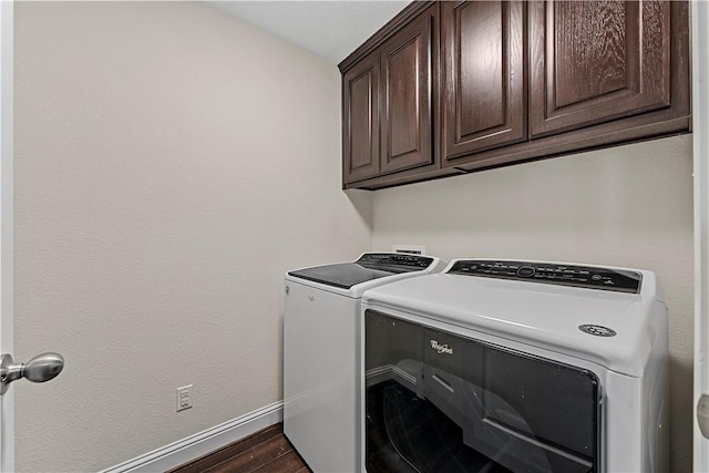 laundry room featuring cabinets, washing machine and dryer, and dark wood-type flooring