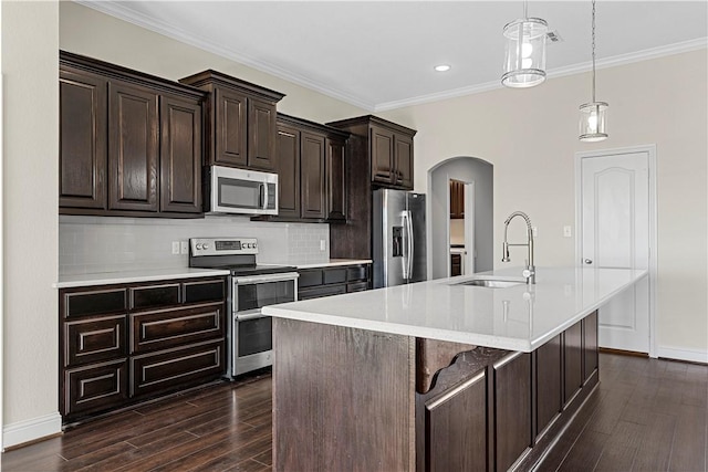 kitchen featuring sink, dark wood-type flooring, stainless steel appliances, an island with sink, and a kitchen bar